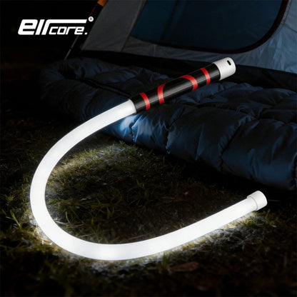 Flexible LED light glowing in a U-shape on grass beside a tent and sleeping bag at night