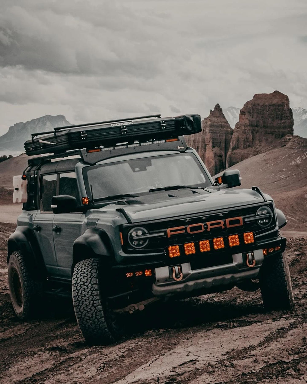 Off-road SUV with a roof tent parked in a desert canyon, recovery shackles fitted to the front bumper