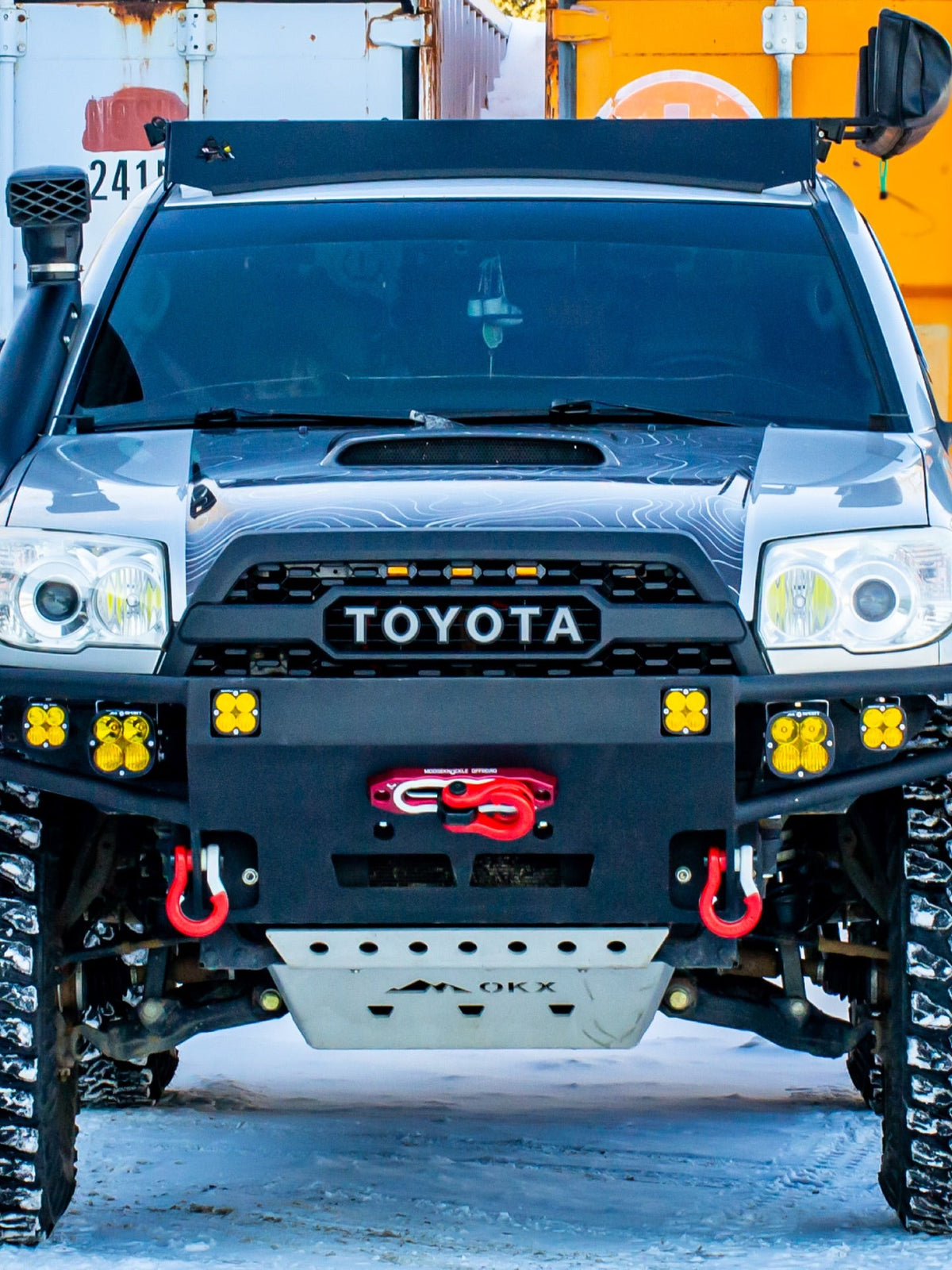 Pickup truck fitted with recovery shackles, parked on packed snow